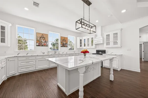 a large white kitchen with a center island wooden floor and stainless steel appliances