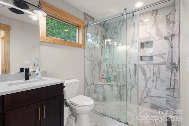 a bathroom with a sink a toilet a glass door shower and a mirror