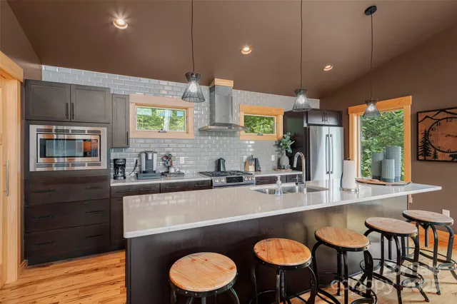 a kitchen with stainless steel appliances granite countertop a sink a stove a dining table and chairs with wooden floor