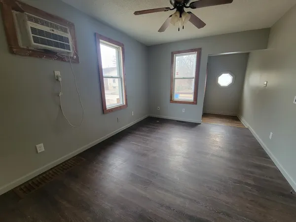 a view of an empty room with a window and wooden floor