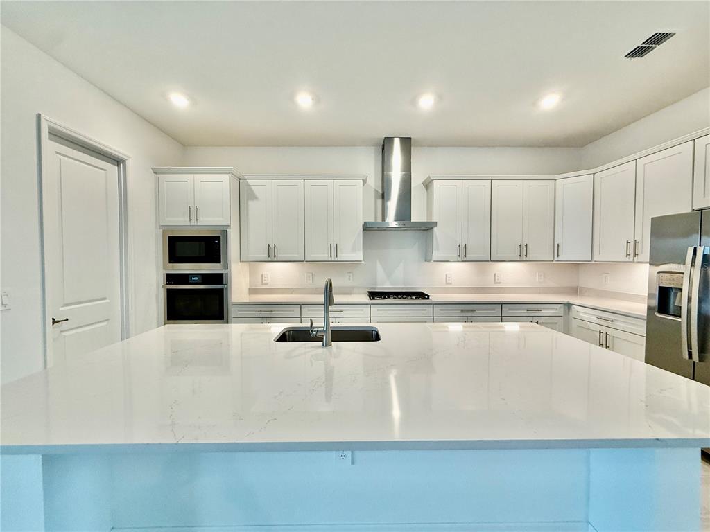 19107 Cherrystone Way Lakewood Ranch, FL 34211 - Photo 7 of 30 a large kitchen with stainless steel appliances a large counter top a stove and a refrigerator