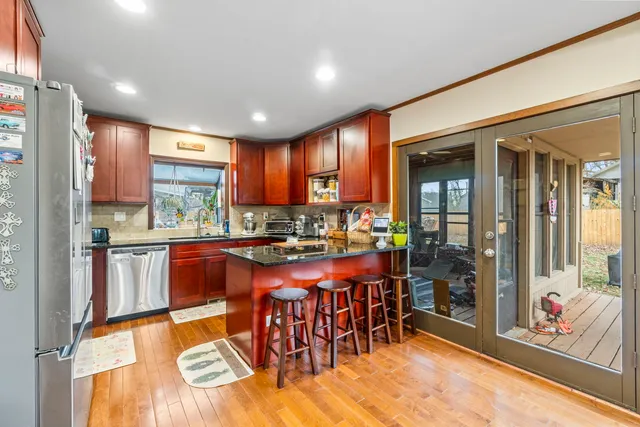 a kitchen with stainless steel appliances granite countertop a refrigerator a sink dishwasher a stove and a dining table with the view of kitchen