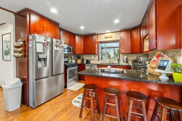 a kitchen with granite countertop stainless steel appliances a sink and a refrigerator