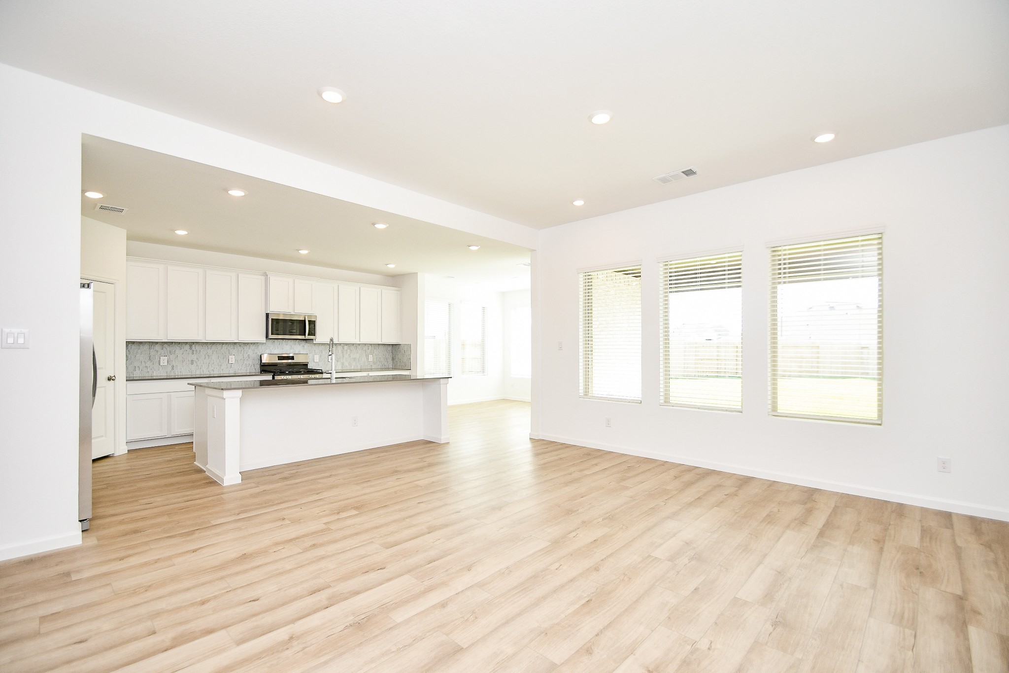 5624 Frst Cv Drive Rosenberg, TX 77469 - Photo 22 of 32 a large white kitchen with kitchen island a sink wooden floor and a living room view