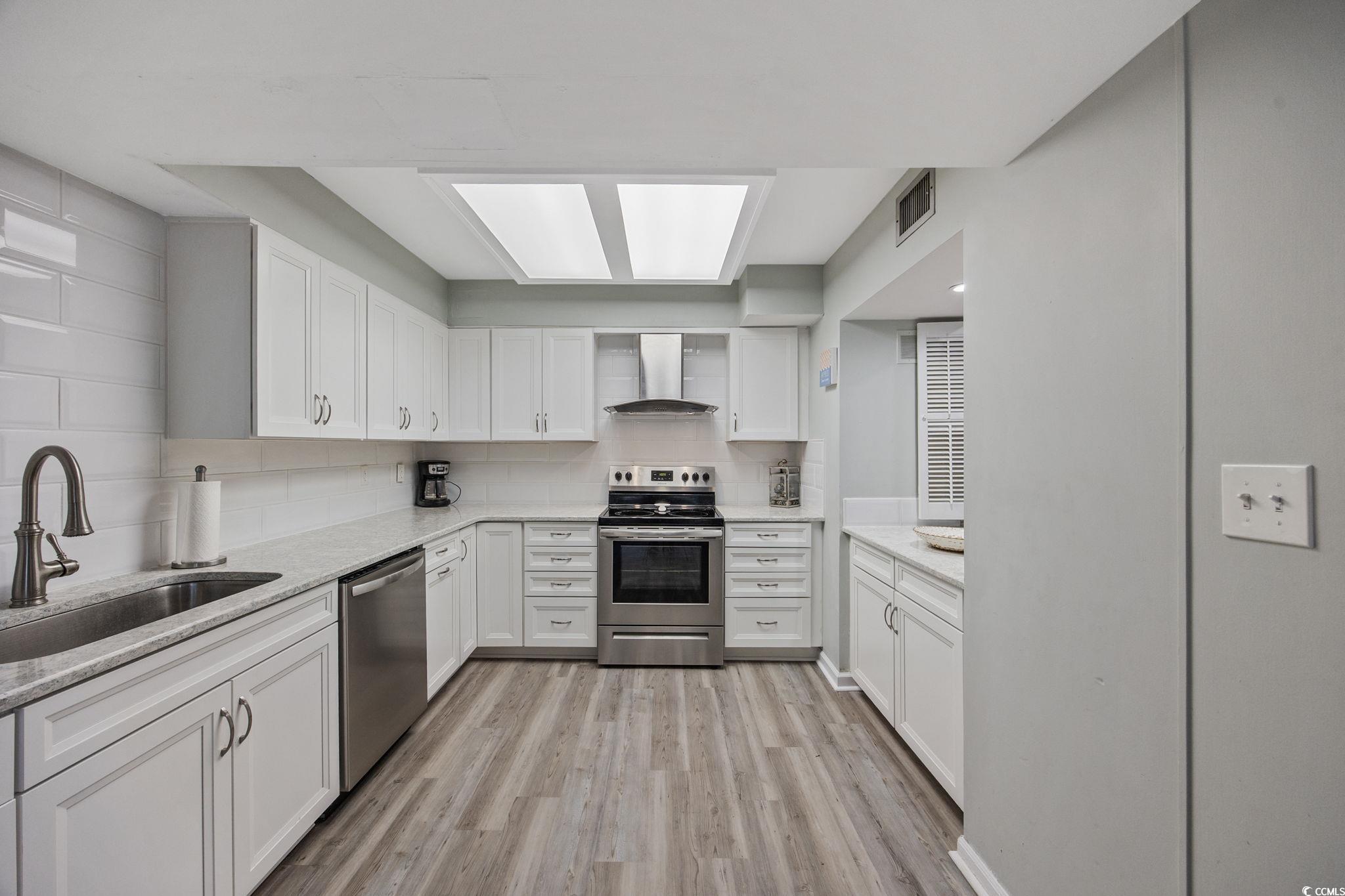 64 Bamboo Loop, Unit 161 Georgetown, SC 29440 - Photo 13 of 31 Kitchen with wall chimney range hood, appliances with stainless steel finishes, a sink, light wood-type flooring, and white cabinetry