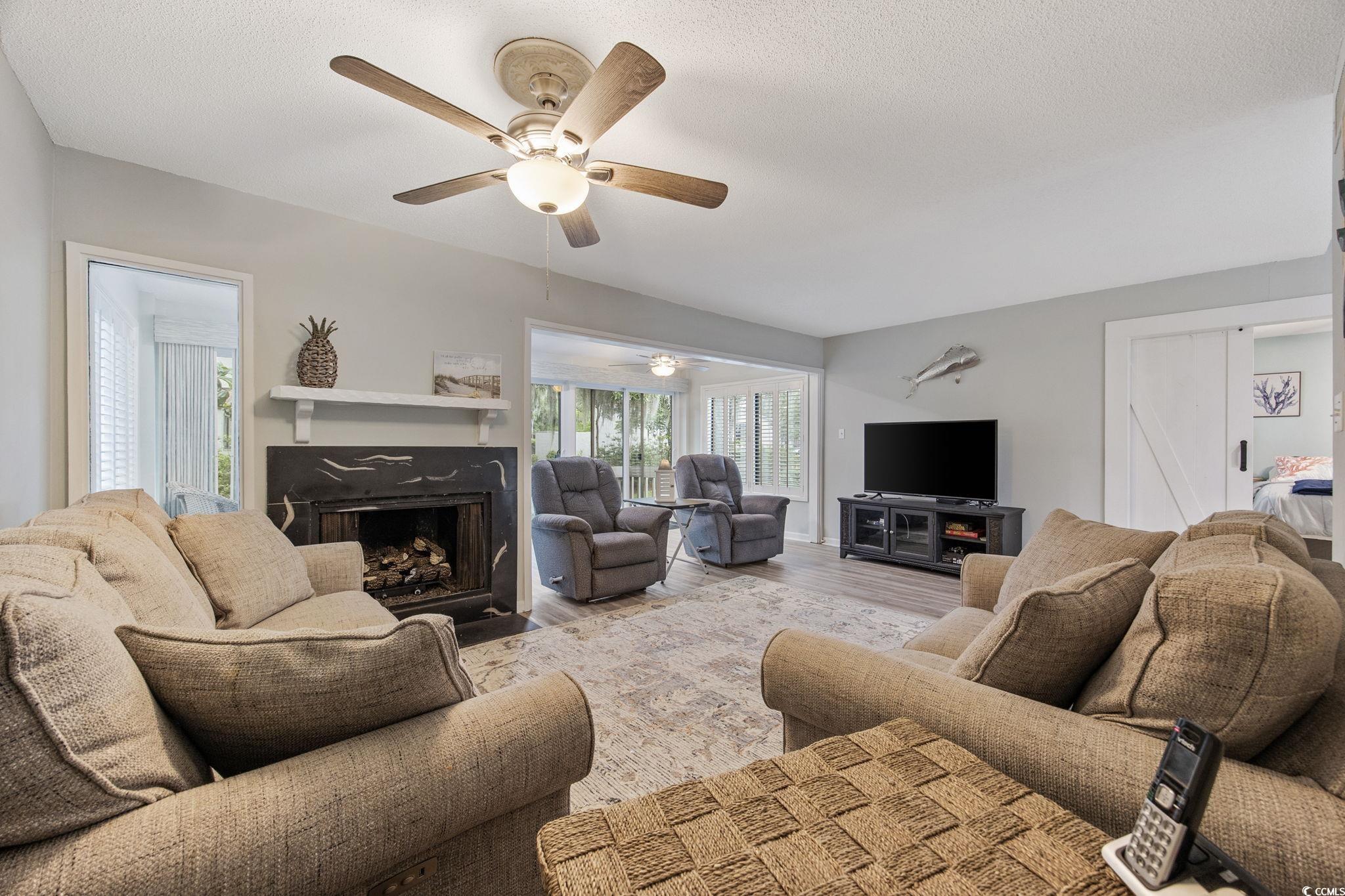 64 Bamboo Loop, Unit 161 Georgetown, SC 29440 - Photo 17 of 31 Living area featuring a ceiling fan, a fireplace with flush hearth, wood finished floors, and a textured ceiling