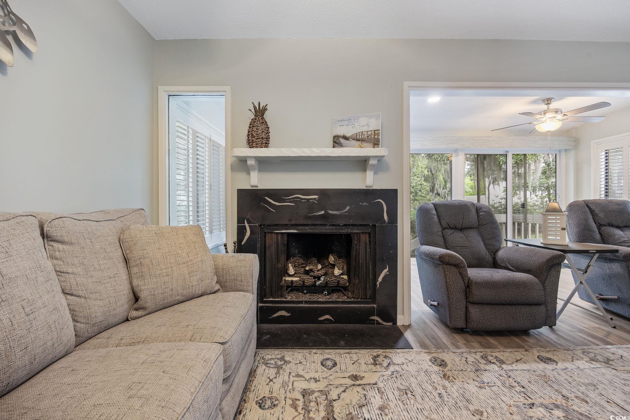 64 Bamboo Loop, Unit 161 Georgetown, SC 29440 - Photo 18 of 31 Living area featuring wood finished floors, a fireplace with flush hearth, and a ceiling fan