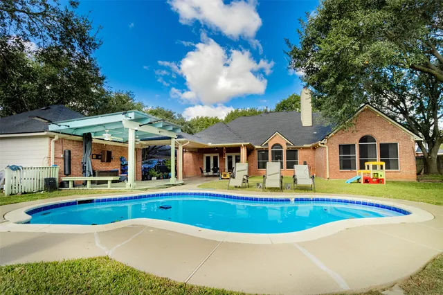 a view of pool with umbrella and chairs