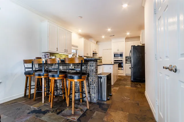 a kitchen with stainless steel appliances a table chairs and a refrigerator