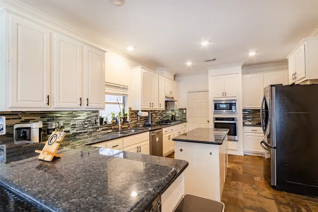 a kitchen with stainless steel appliances granite countertop a sink a stove and a refrigerator
