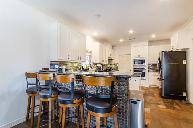 a kitchen with stainless steel appliances granite countertop a table chairs stove a refrigerator and a microwave