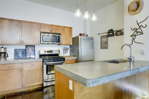 a kitchen with stainless steel appliances granite countertop a sink a stove and a refrigerator