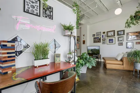 a living room with stainless steel appliances furniture a flat screen tv and a dining table