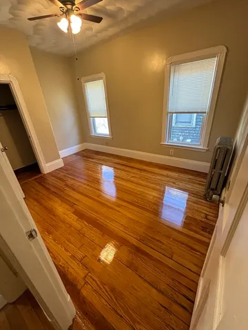 a view of a room with a ceiling fan and wooden floor