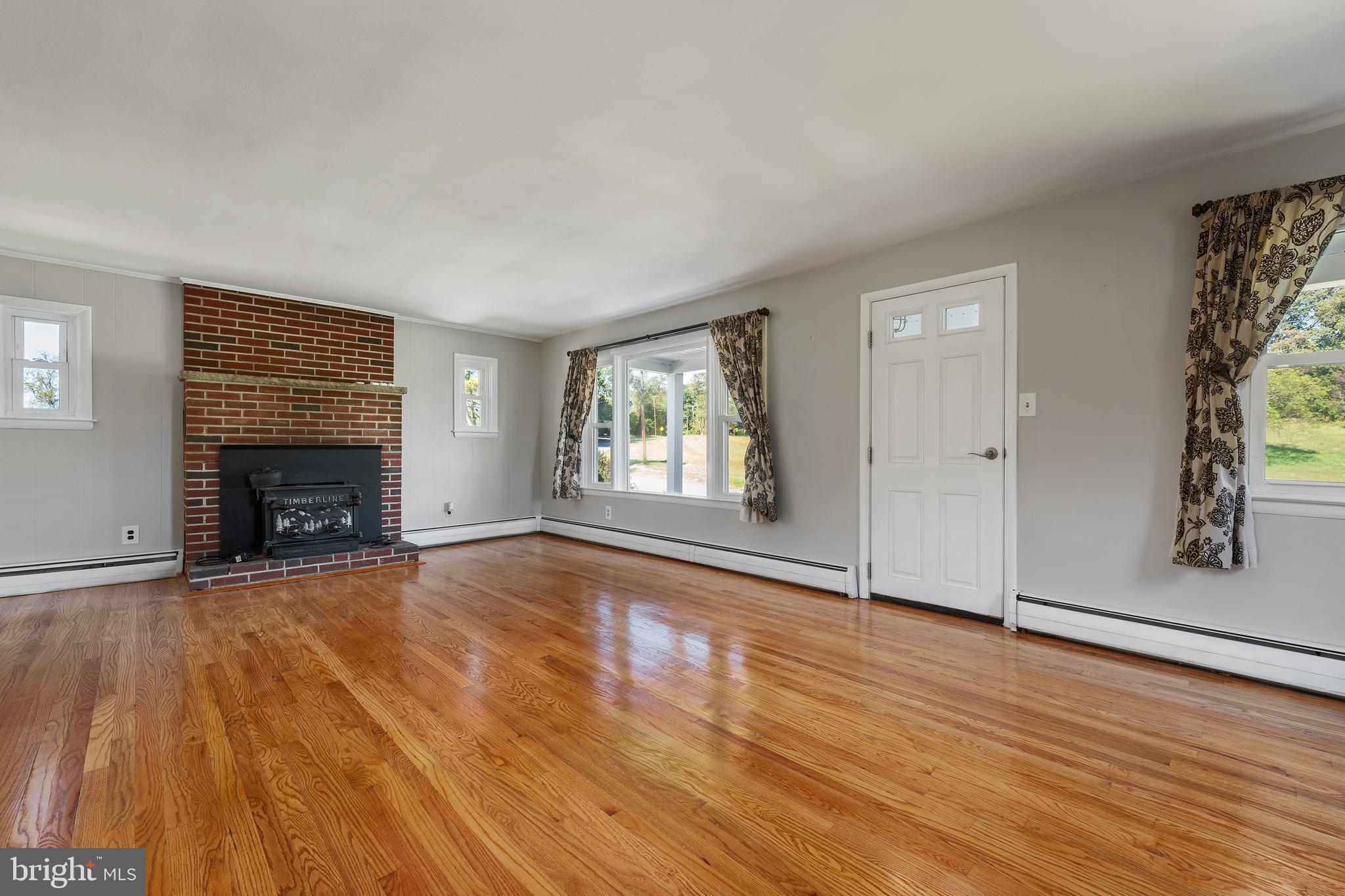 16357 Trenton Road Upperco, MD 21155 - Photo 19 of 68 an empty room with wooden floor fireplace and windows