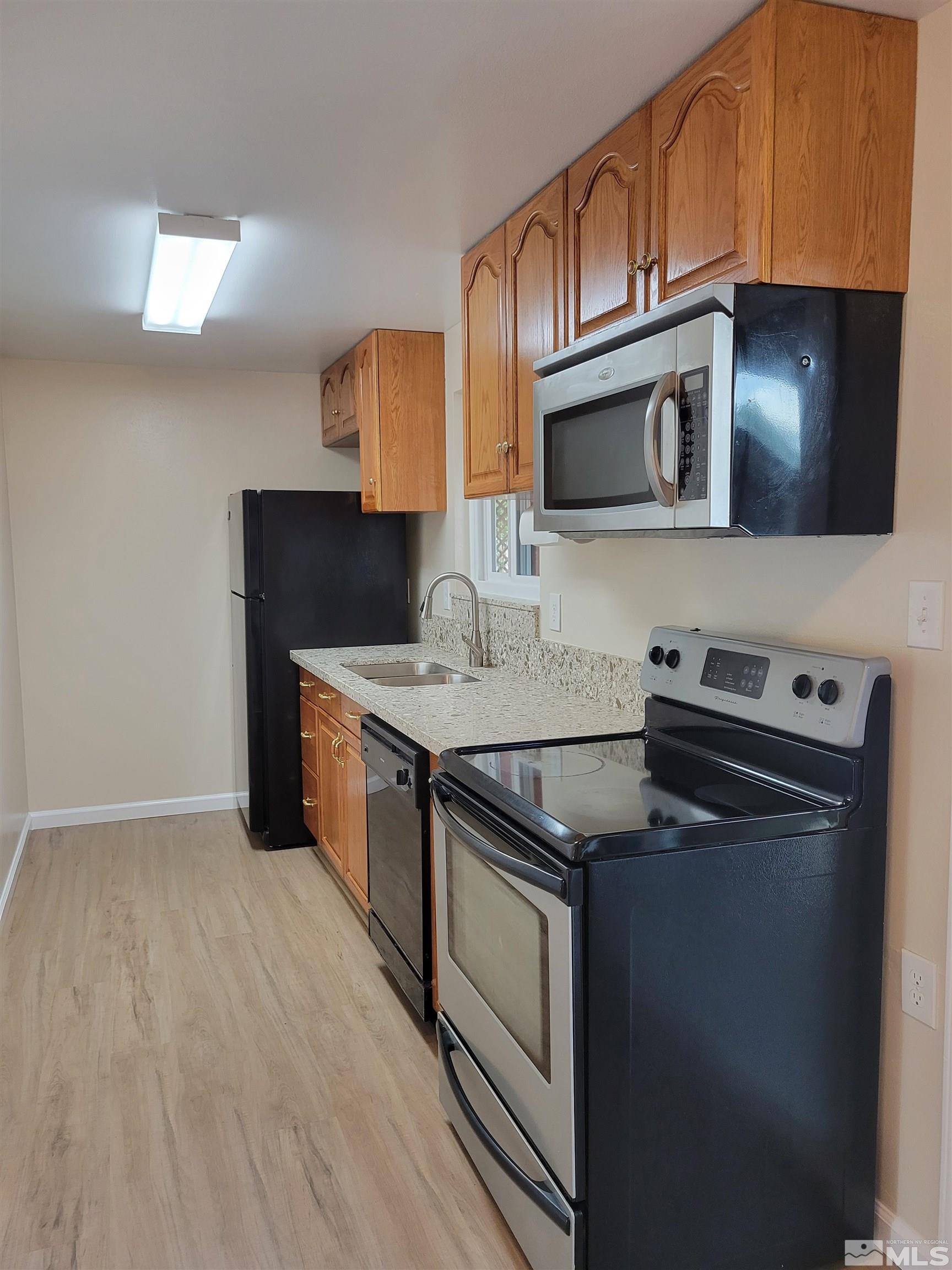 9085 Fremont Way Reno, NV 89506 - Photo 3 of 10 a kitchen with stainless steel appliances granite countertop a stove a microwave and a sink