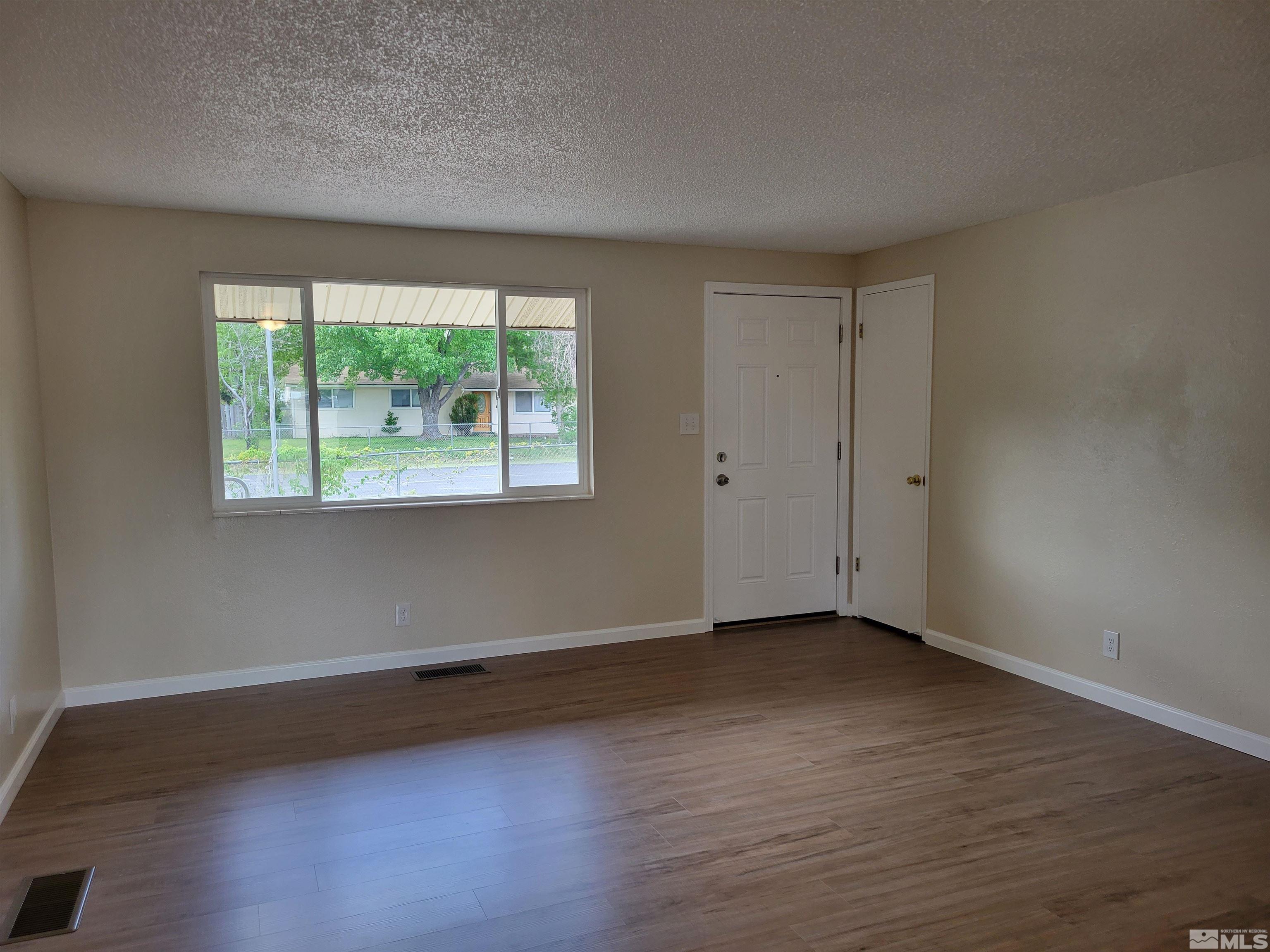 9085 Fremont Way Reno, NV 89506 - Photo 4 of 10 a view of an empty room with wooden floor and a window