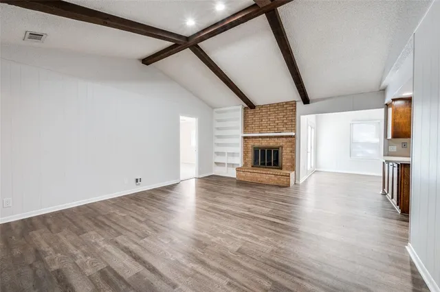 a view of empty room with wooden floor and fireplace