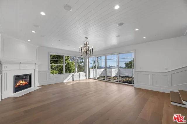 a view of an empty room with wooden floor and a fireplace