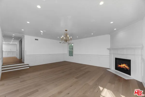 a view of an empty room with wooden floor fireplace and a window