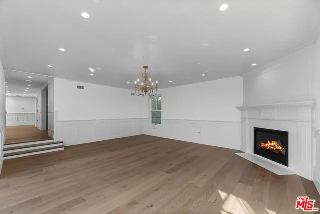a view of an empty room with wooden floor fireplace and a window
