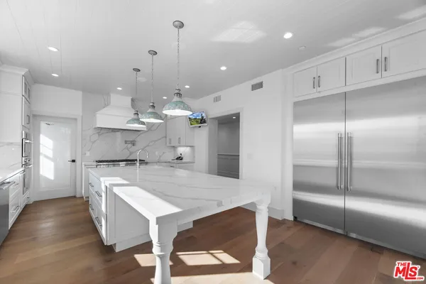 a large kitchen with kitchen island a chandelier and a view of living room