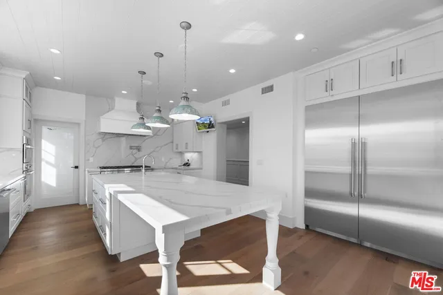 a large kitchen with kitchen island a chandelier and a view of living room