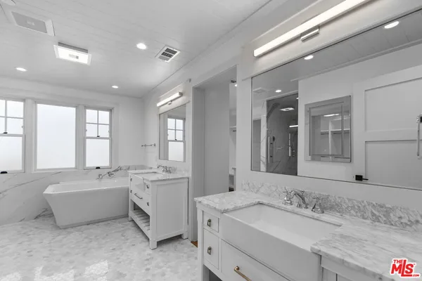 a bathroom with a sink double vanity mirror and a bathtub