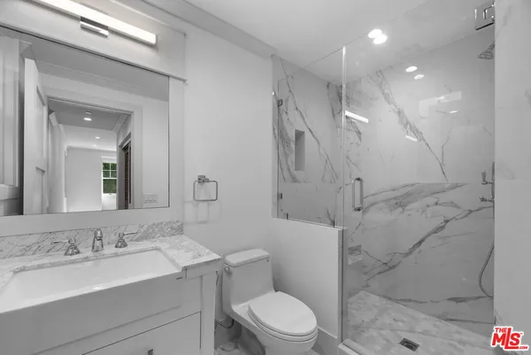 a bathroom with a granite countertop sink a toilet and shower