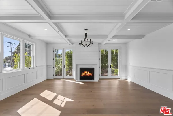 a view of an empty room with wooden floor fireplace and a window