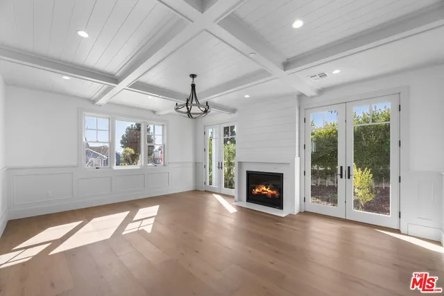 a view of an empty room with wooden floor fireplace and a window