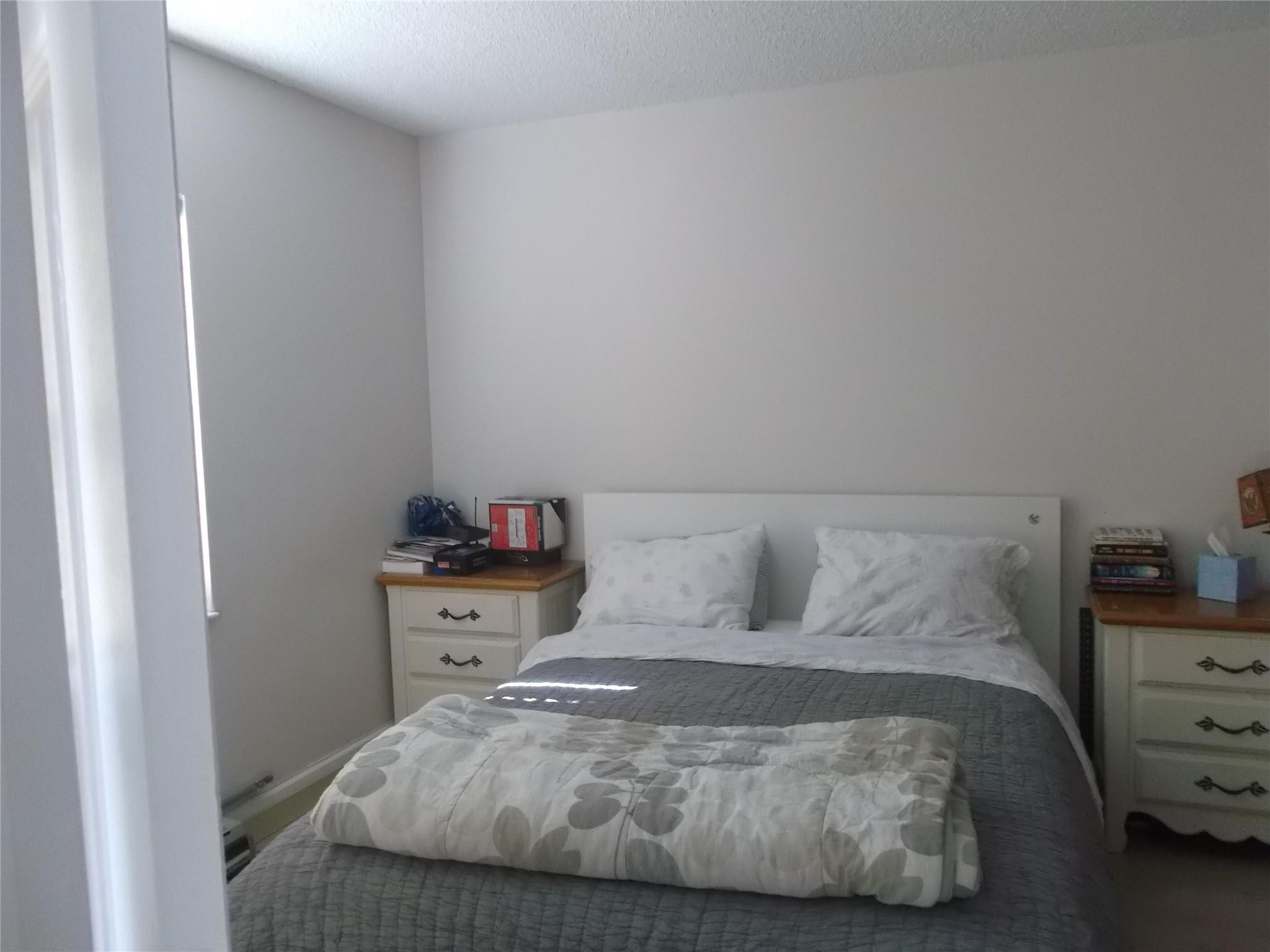 2955 Riverside Drive, Unit 103 Coral Springs, FL 33065 - Photo 13 of 26 a bedroom with a bed and a lamp on the dresser