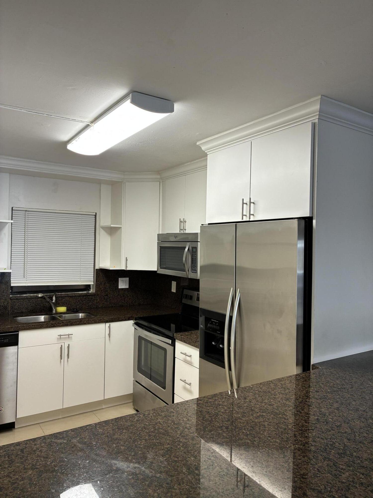 2955 Riverside Drive, Unit 103 Coral Springs, FL 33065 - Photo 7 of 26 a kitchen with granite countertop a refrigerator and cabinets