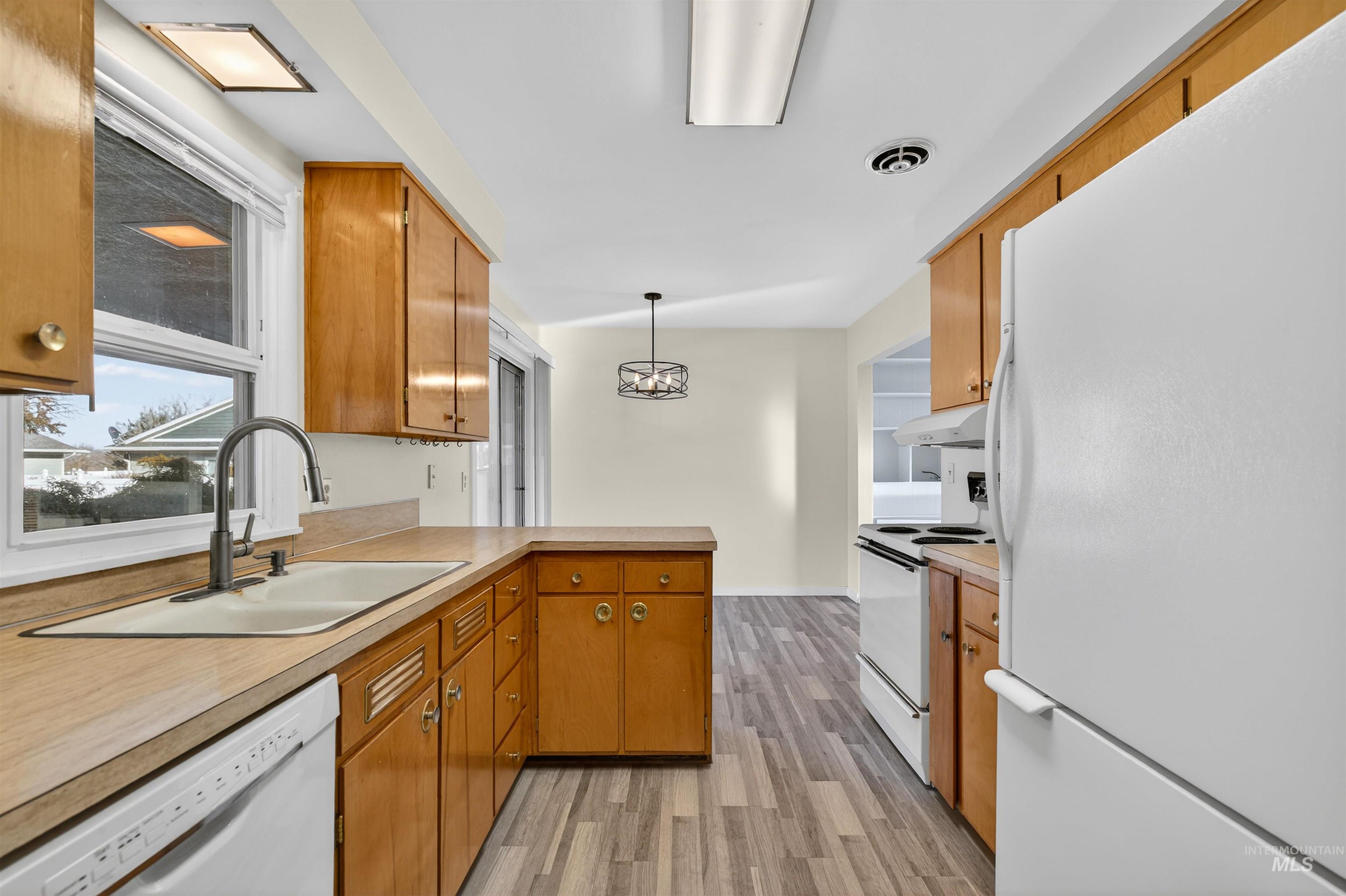 609 Grelle Avenue Lewiston, ID 83501 - Photo 12 of 48 Kitchen with white appliances, wood finish cabinetry, light countertops, light wood-style flooring, and a peninsula