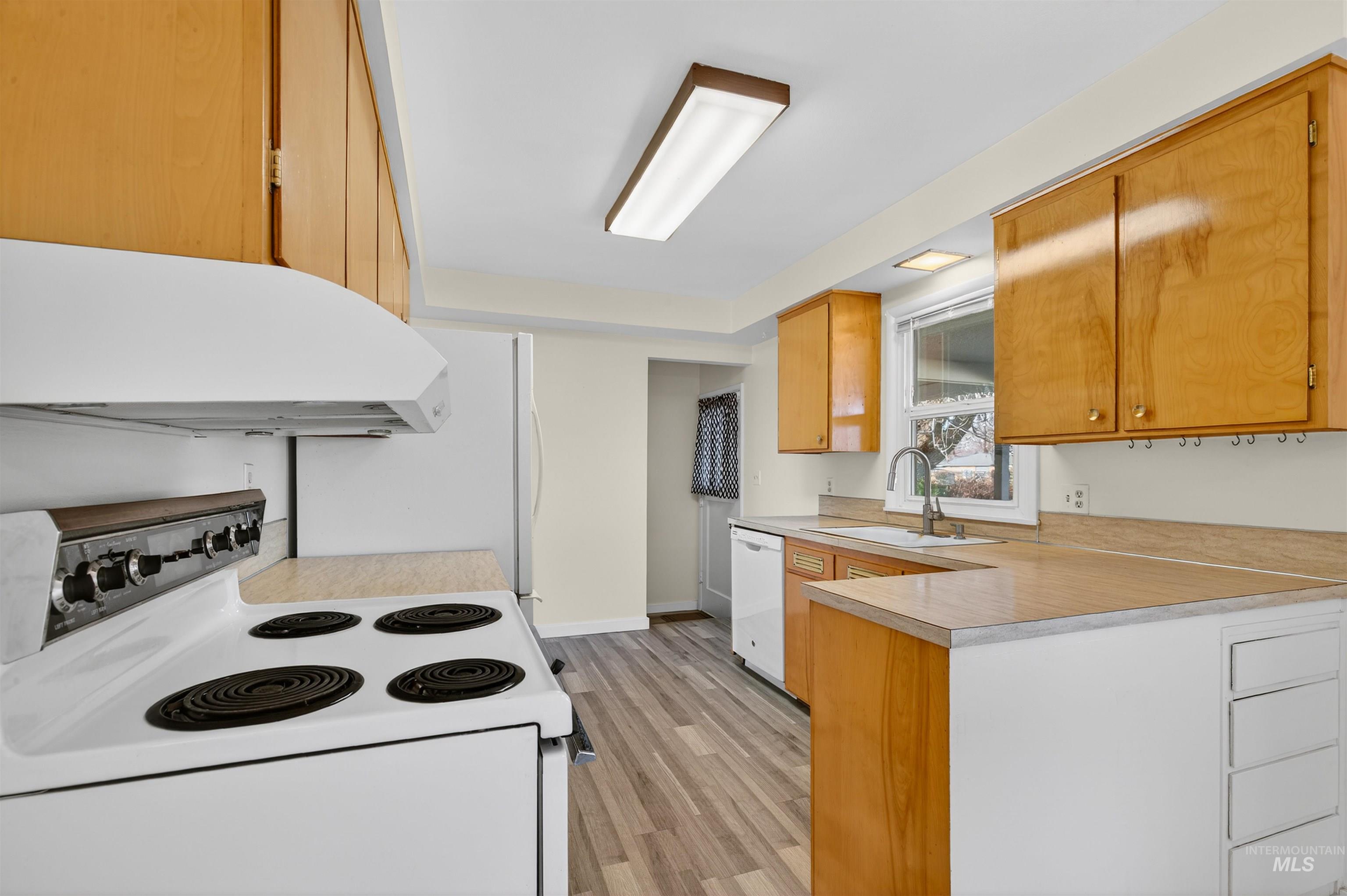 609 Grelle Avenue Lewiston, ID 83501 - Photo 14 of 48 Kitchen featuring white appliances, a peninsula, light countertops, wood finish cabinets, and light wood-type flooring