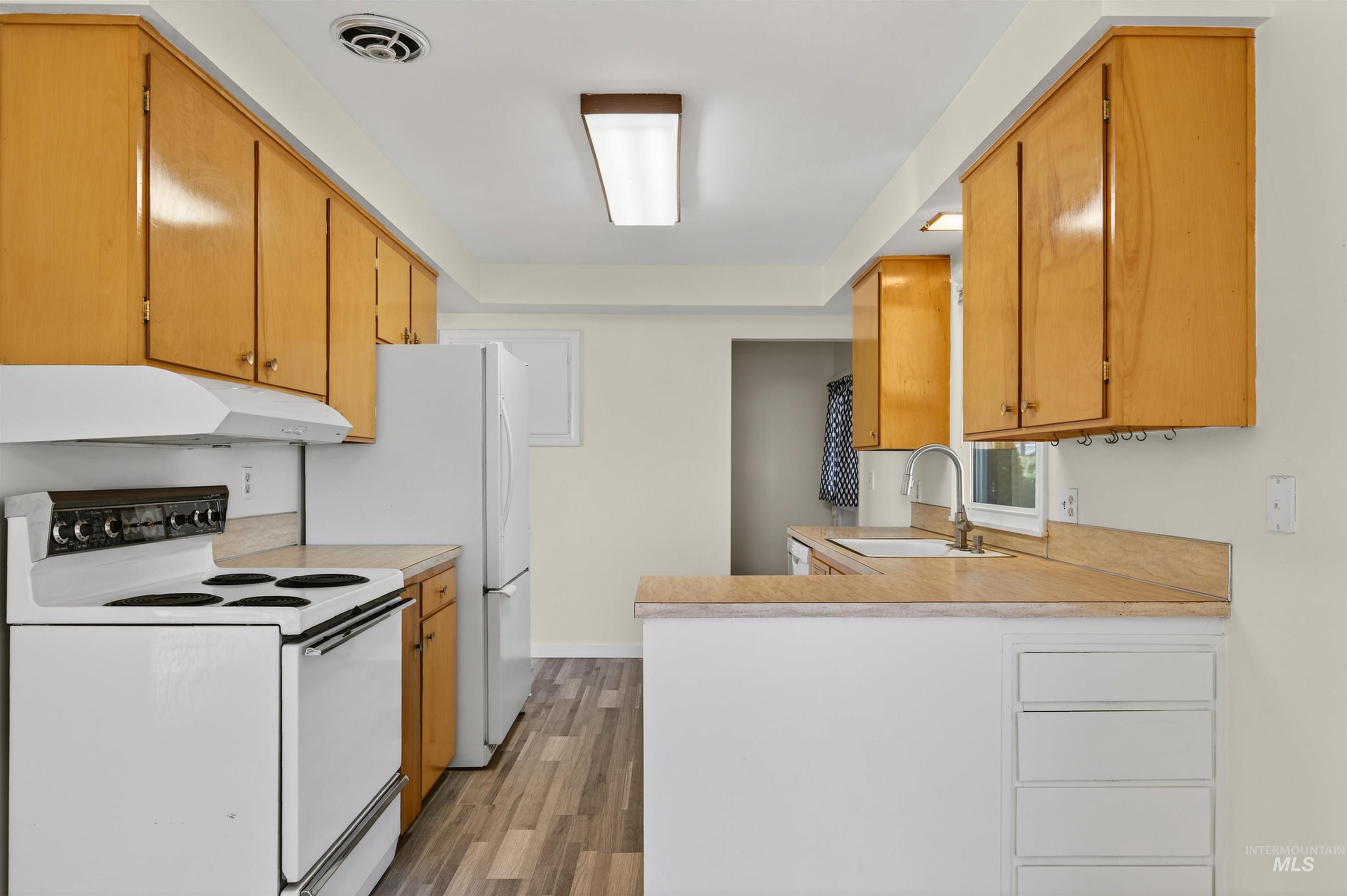 609 Grelle Avenue Lewiston, ID 83501 - Photo 15 of 48 Kitchen with white appliances, light countertops, a peninsula, and light wood finished floors