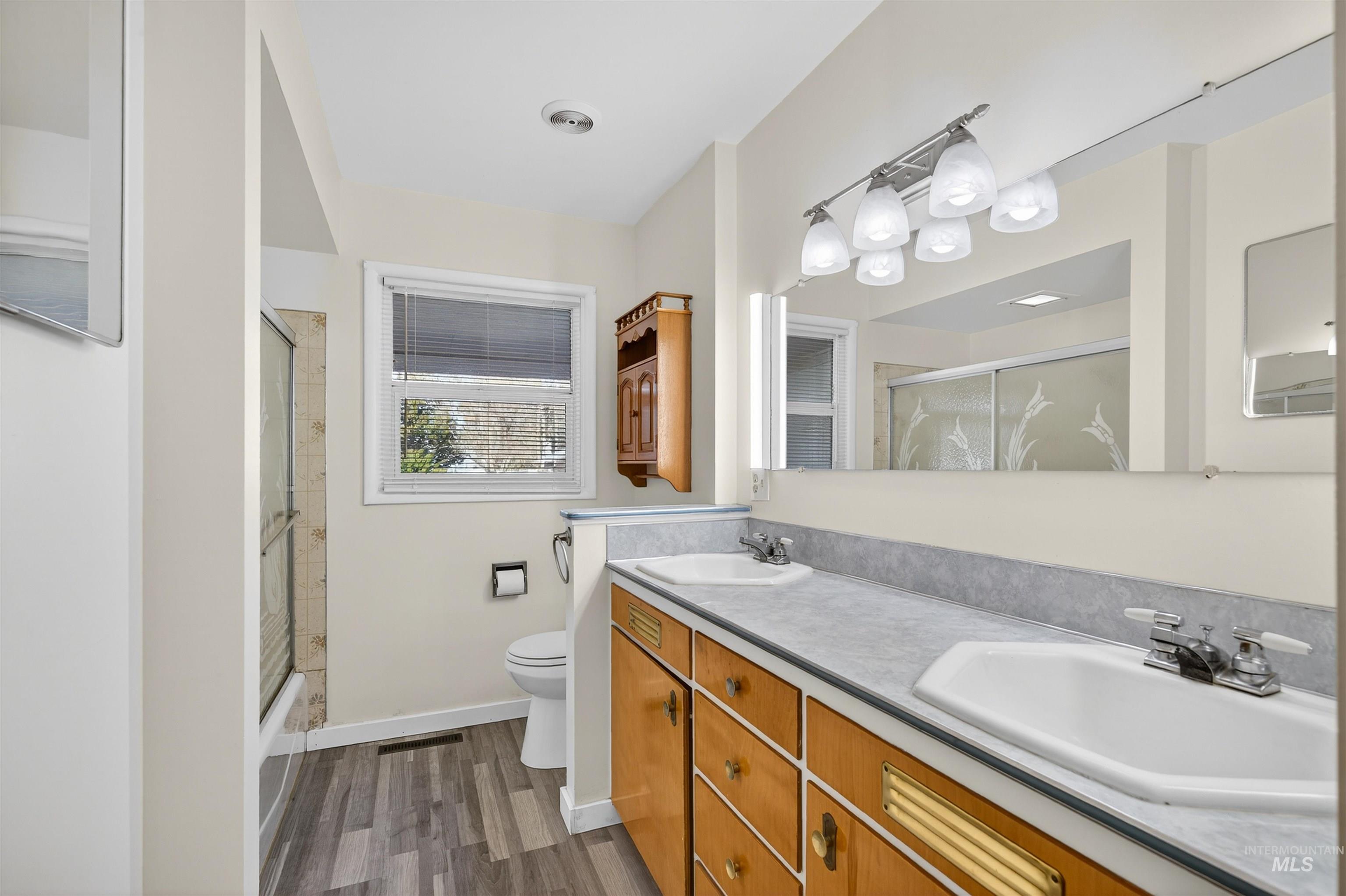 609 Grelle Avenue Lewiston, ID 83501 - Photo 20 of 48 Full bathroom with double vanity, dark wood-style floors, and shower / bath combination with glass door