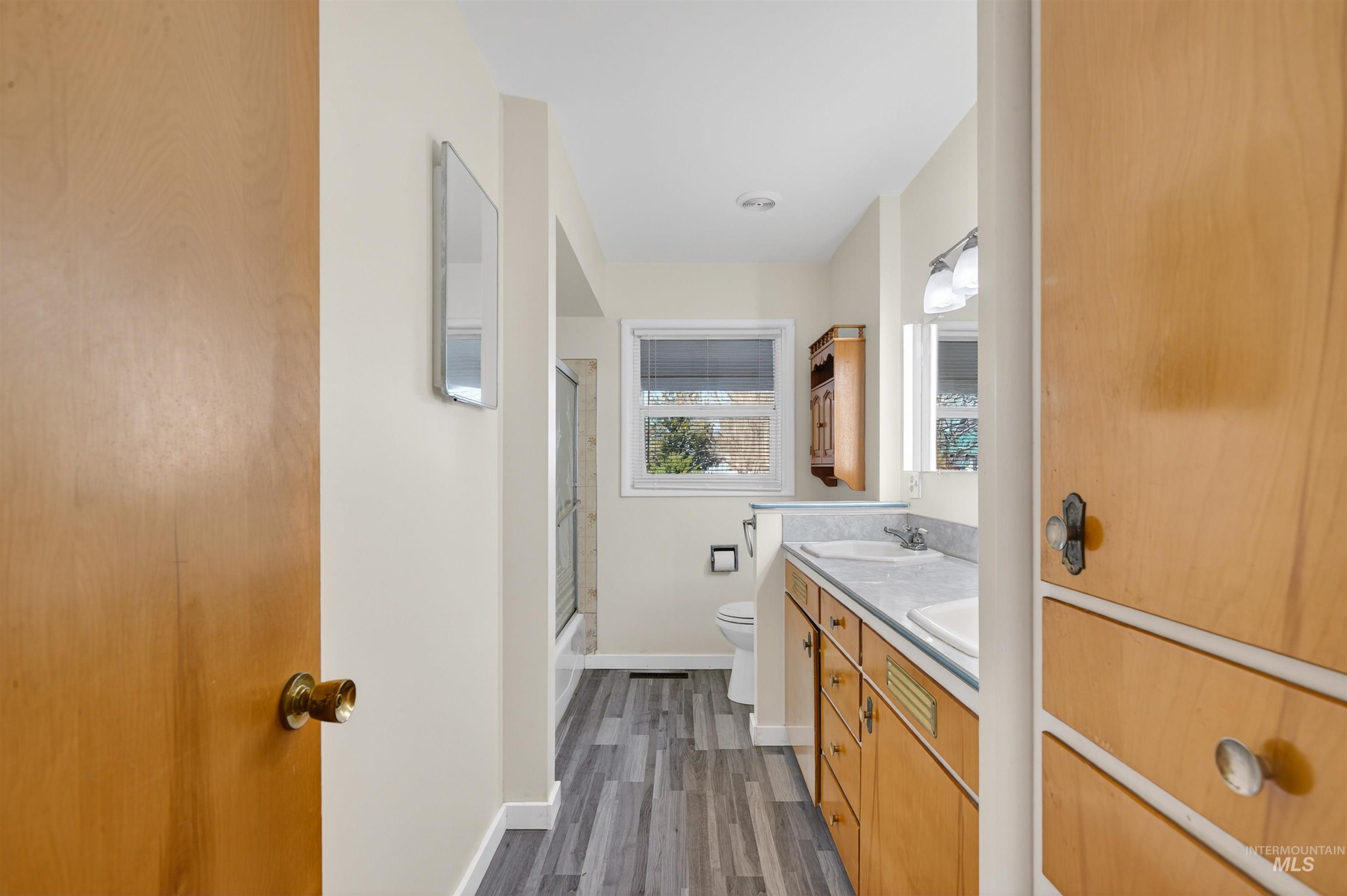 609 Grelle Avenue Lewiston, ID 83501 - Photo 21 of 48 Full bathroom with double vanity, enclosed tub / shower combo, and dark wood-style flooring