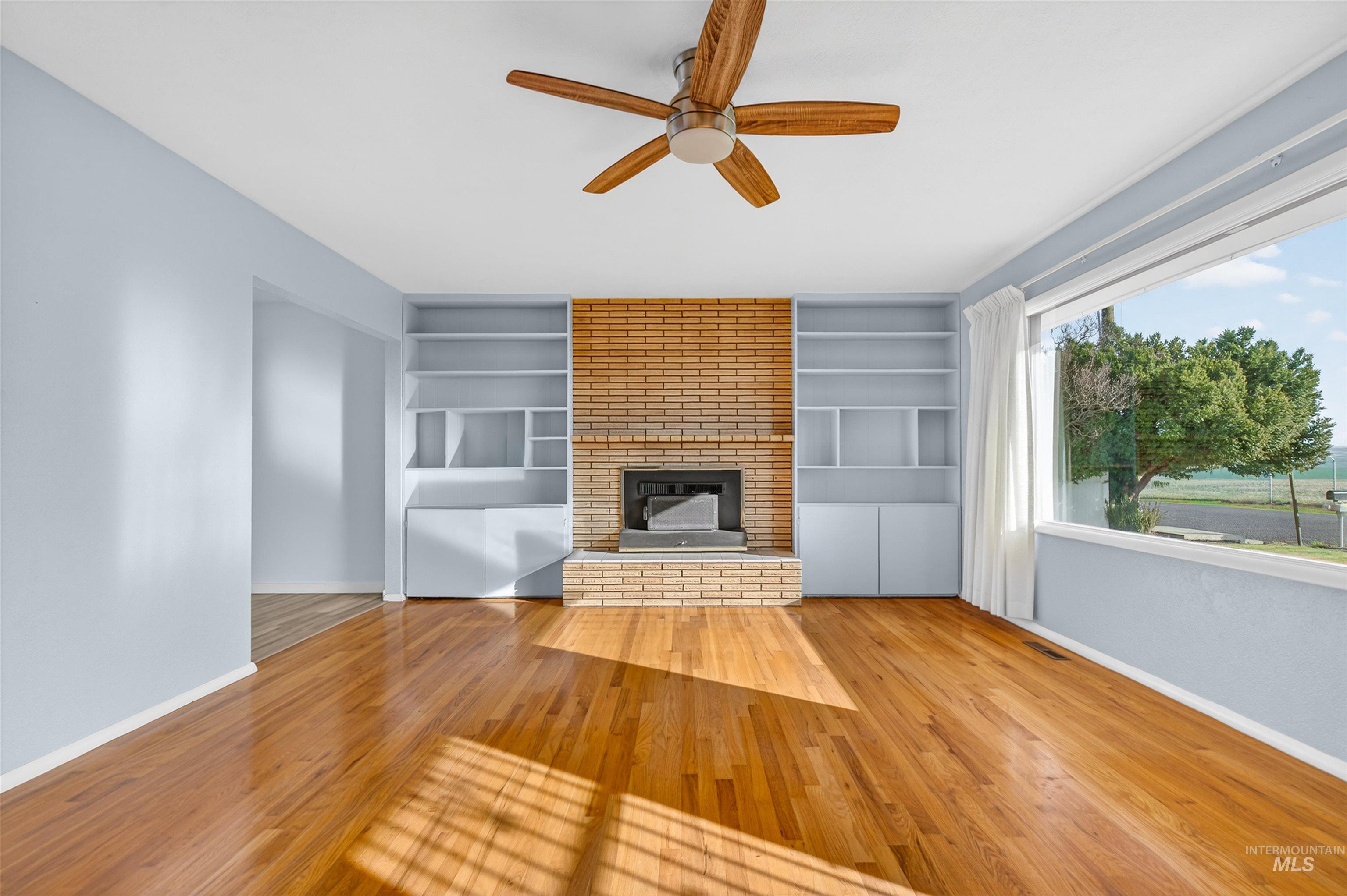 609 Grelle Avenue Lewiston, ID 83501 - Photo 6 of 48 Unfurnished living room with ceiling fan, built in features, hardwood / wood-style floors, and a fireplace