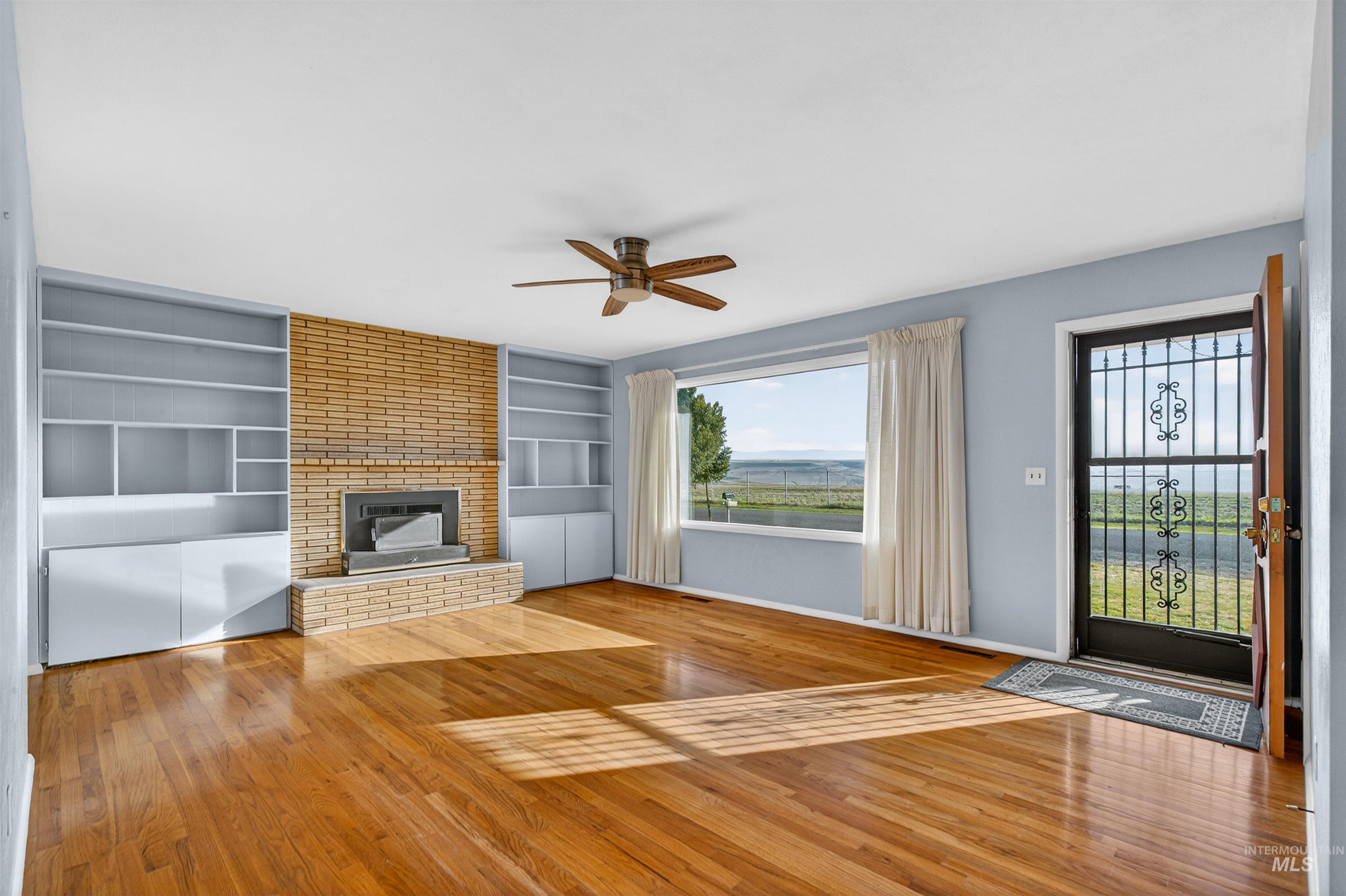 609 Grelle Avenue Lewiston, ID 83501 - Photo 9 of 48 Unfurnished living room featuring ceiling fan, hardwood / wood-style floors, built in shelves, and a fireplace