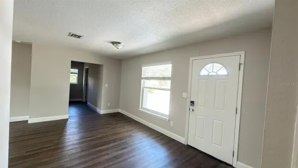 an empty room with wooden floor and windows