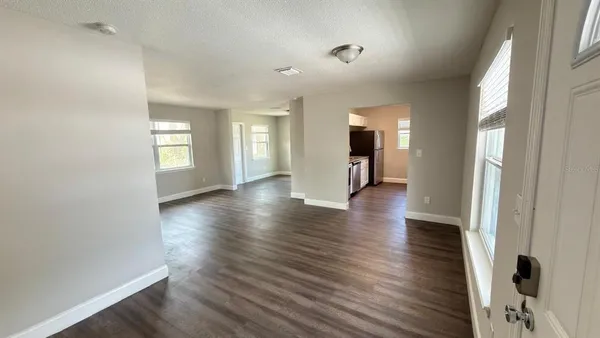 an empty room with wooden floor and windows