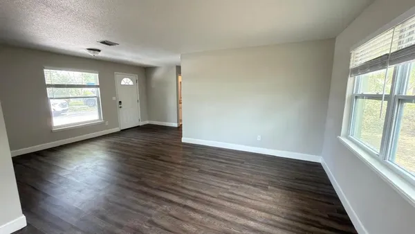 an empty room with wooden floor and windows