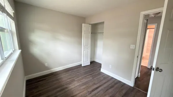 an empty room with wooden floor and window