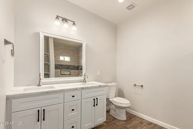 a bathroom with a granite countertop toilet a sink a mirror and a window