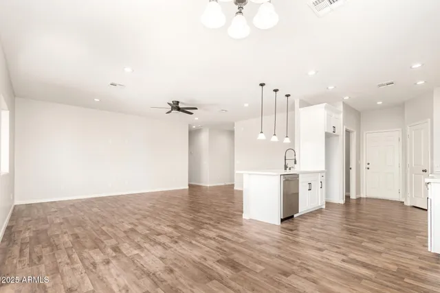 a view of empty room with wooden floor and kitchen
