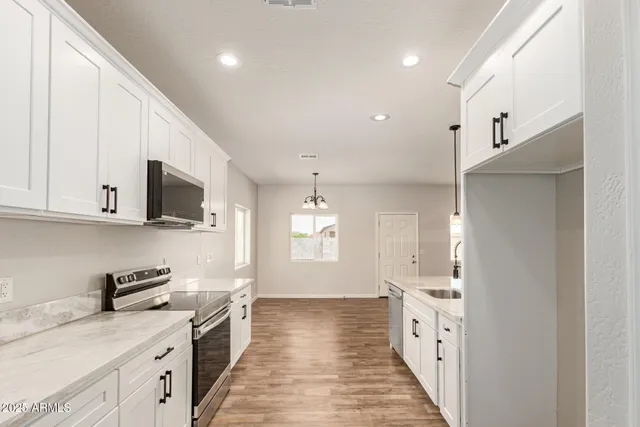 a large kitchen with stainless steel appliances granite countertop a lot of counter space and wooden floor