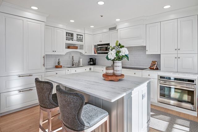 a kitchen with stainless steel appliances granite countertop a stove a sink a microwave a dining table and chairs