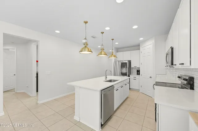 a large white kitchen with a sink and dishwasher a refrigerator with white cabinets