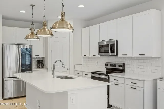 a kitchen with stainless steel appliances a stove a sink and white cabinets